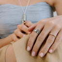 Velum stainless steel ring with drapery-inspired curved design and open back, worn on finger