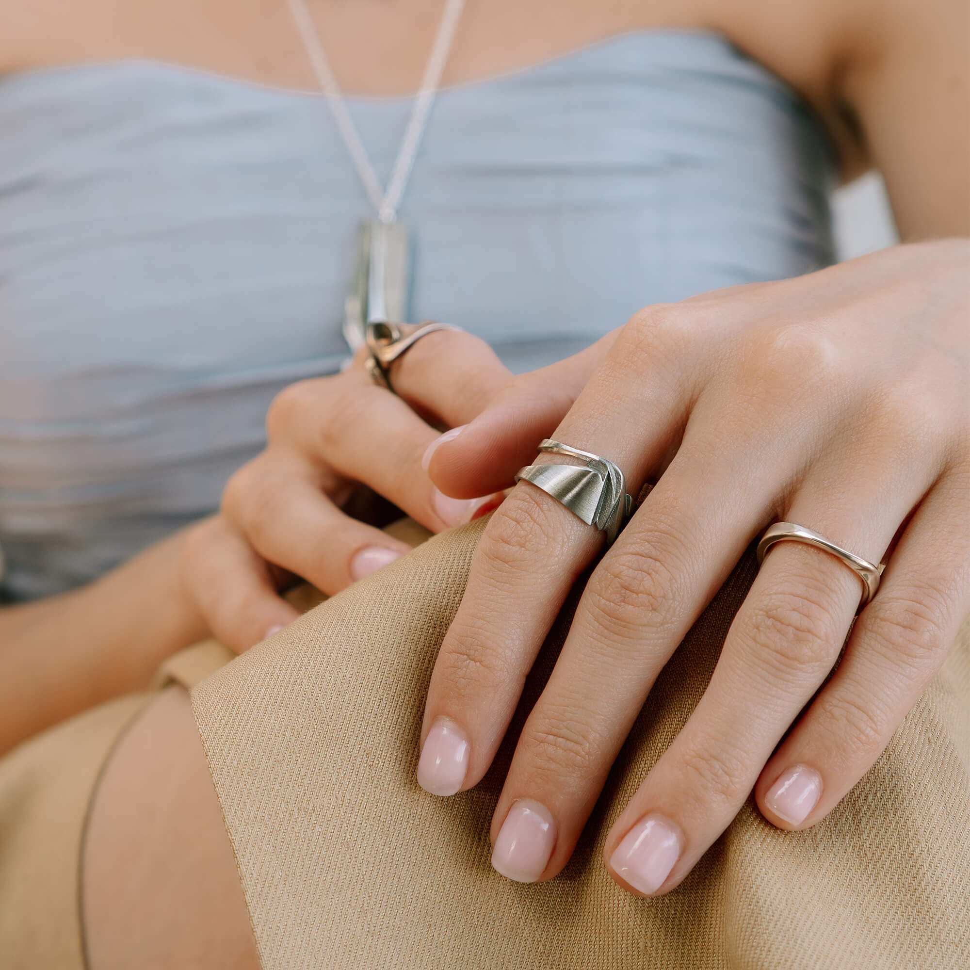 Velum stainless steel ring with drapery-inspired curved design and open back, worn on finger
